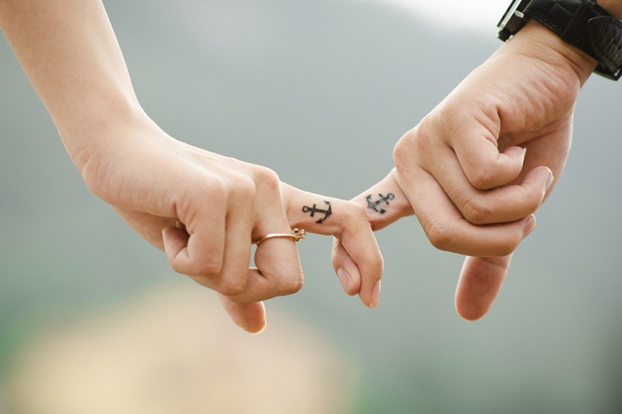 Image d'en-tête de l'article Je Réalise " Communiquer sur la sexualité au sein du couple ", sur laquelle l'on voit une main de femme et une main d'homme, les index entrelacés, tatoués d'une ancre.