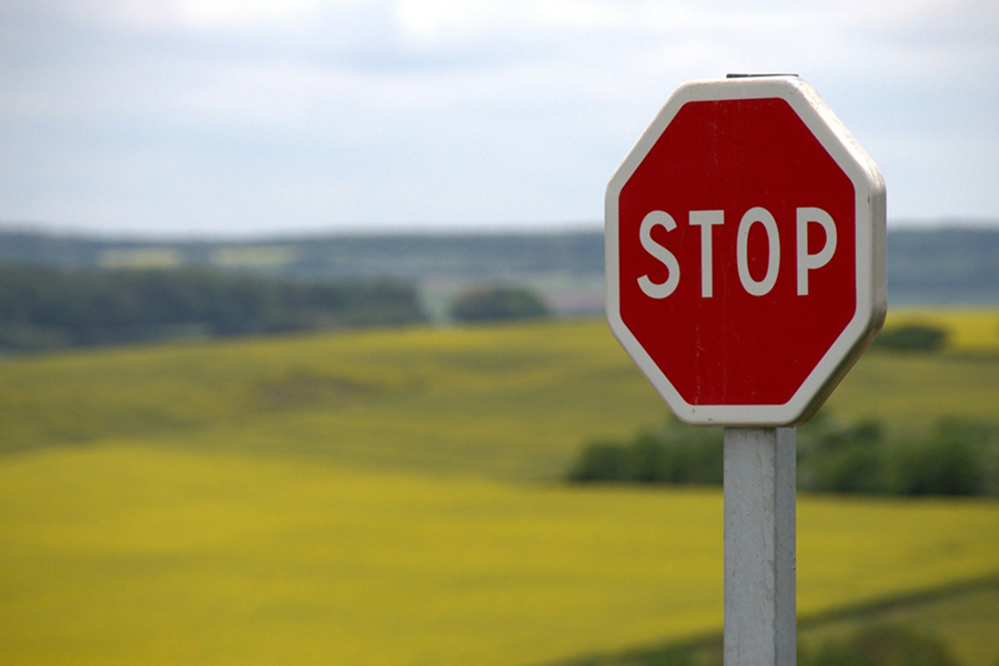 Image d'en-tête de l'article Je Réalise " Fixer ses limites et les faire respecter ", sur laquelle l'on voit un panneau " Stop " rouge, avec un champ en arrière-plan.