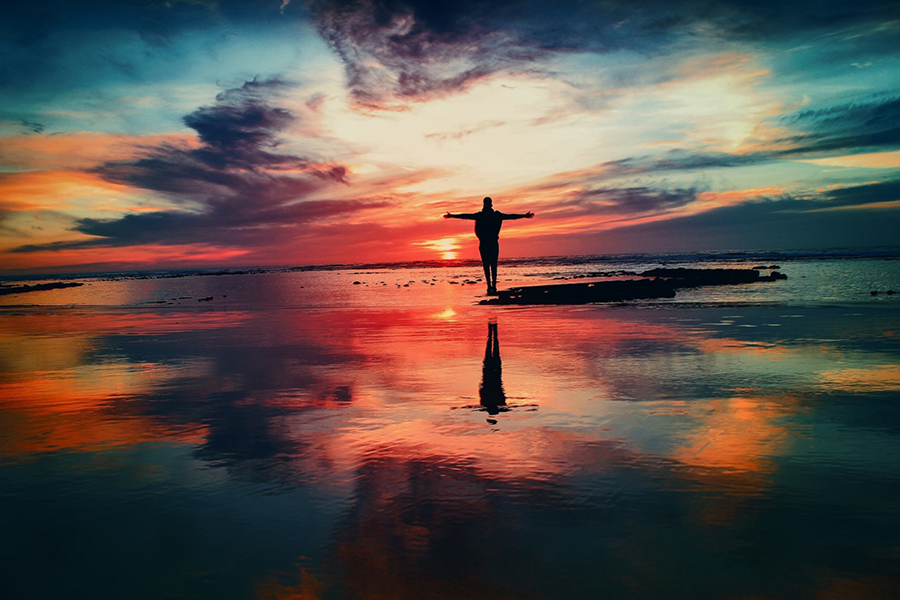 Image d'en-tête de l'article Je Réalise " Stop au stress #2 Grâce au mouvement ", sur laquelle l'on voit une silhouette de dos, les bras écartés, dans un bord de mer au crépuscule.
