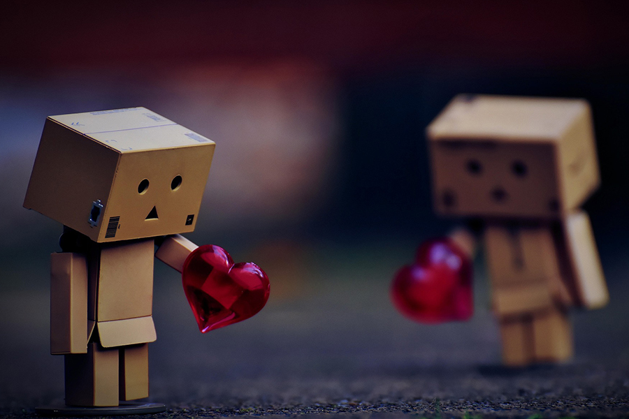 Image d'en-tête de l'article Je Réalise " Surmonter la jalousie romantique ", sur laquelle l'on voit deux bonhommes construits en carton, la tête baissée, tenant chacun un coeur rouge dans la main.