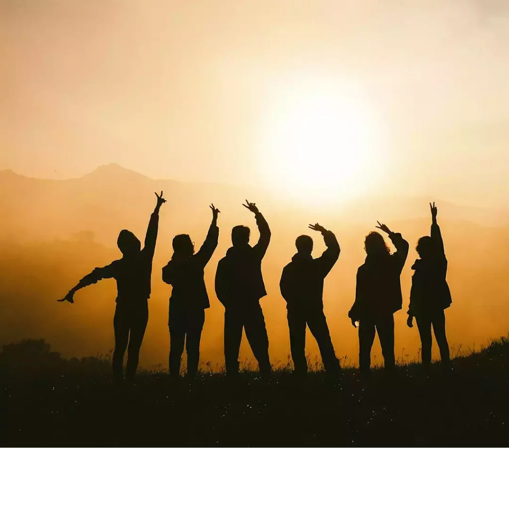 Image d'en-tête de l'article Je Réalise : " La Communication NonViolente - un outil puissant pour améliorer nos relations ", sur laquelle l'on voit les silhouettes d'un groupe d'amis heureux au sommet d'une montagne au soleil couchant.