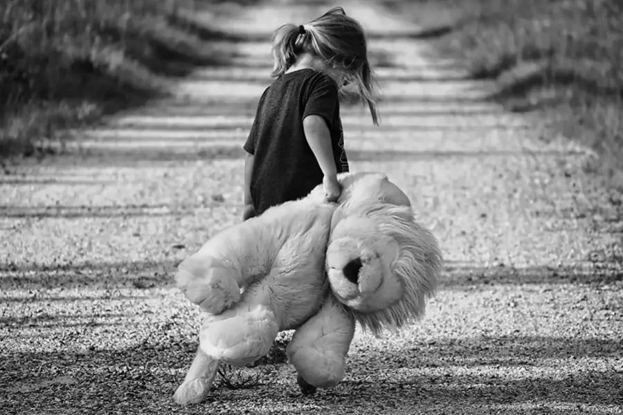 Image d'en-tête de l'article Je Réalise " Comment gérer la déception et la surmonter ? ", sur laquelle l'on voit une petite fille en noir et blanc qui marche sur un chemin, de dos et la tête baissée, traînant un gros ours en peluche derrière elle.
